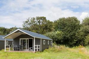 een klein huis met een veranda en een terras bij Strand49 Glamping Sint Maartenszee in Sint Maartensvlotbrug