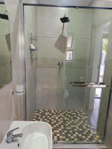 a shower with a glass door next to a sink at Lady Daisy Boutique Guesthouse in Rustenburg