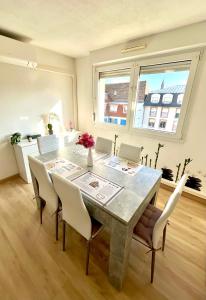 a dining room with a table with white chairs at Appartement Cosy & Spacieux - Centre ville in Strasbourg