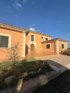 une grande maison orange avec une allée en face de celle-ci dans l'établissement Mondrago Casa, Ruhige Finca mit Pool bei Santanyí, à Îles Baléares