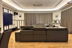 a living room with a large couch and a flat screen tv at 25P Muji Black & White Kajang Villa with 100" TV in Bandar Baru Bangi