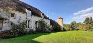 an old house with a tower on a green lawn at Le Nature Lodge in Gy-les-Nonains
