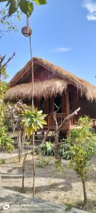 eine Hütte mit Strohdach und einer Palme in der Unterkunft Garden Cottage in Gili Gede