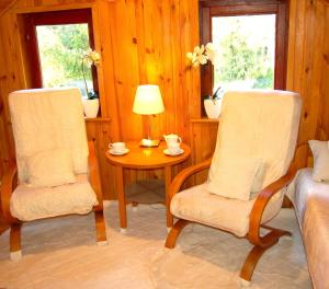 a room with two chairs and a table with a lamp at Domek Zofiówka dostęp na kod in Zofiówka
