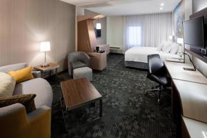 ザ・ウッドランズにあるCourtyard by Marriott Houston North/Shenandoahのベッドとリビングルームがあるホテルの部屋