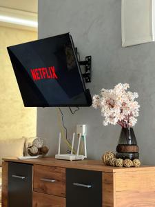a television on top of a wooden dresser with flowers at Modern and quiet apartment in Beni Mellal