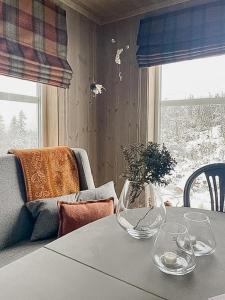 a table with glasses and a vase on top of it at Modern Cabin With Views Of Langsua National Park in Steinsetbygdi