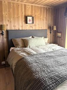 a bedroom with a bed with a wooden wall at Modern Cabin With Views Of Langsua National Park in Steinsetbygdi