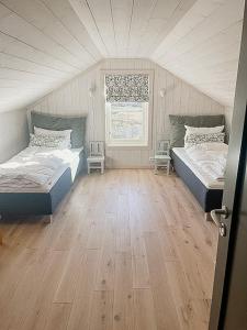 a bedroom with two beds and a wooden floor at Modern Cabin With Views Of Langsua National Park in Steinsetbygdi