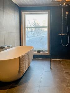 a bathroom with a large tub and a window at Modern Cabin With Views Of Langsua National Park in Steinsetbygdi