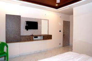 a bedroom with a tv on the wall at Shakthi Homestay in Sringeri +10 photos