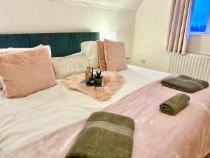 Una cama rosa y blanca con almohadas. en Secluded Hot Tub, With Views - Abergavenny, en Abergavenny