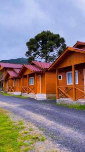 a row of wooden buildings with a tree in the background at Cabanas Coimbra in Urubici