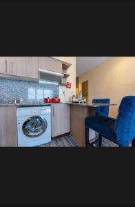 a kitchen with a washing machine and a blue chair at Hayat Plus Hotel in Al Madinah
