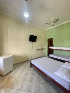 une chambre avec deux lits et une télévision à écran plat dans l'établissement Pousada Três Arcanjos, à Cachoeira Paulista