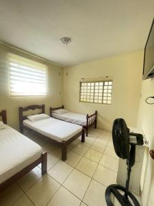 Cette chambre comprend 2 lits et un ventilateur. dans l'établissement Pousada Três Arcanjos, à Cachoeira Paulista
