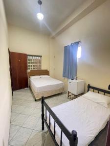 une chambre avec deux lits et une fenêtre dans l'établissement Pousada Três Arcanjos, à Cachoeira Paulista 2 autres photos