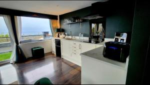 a kitchen with white cabinets and a large window at Carberry Lodge in Musselburgh