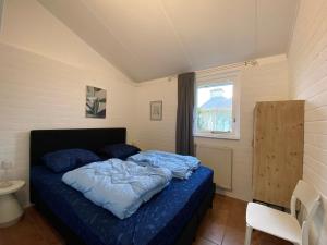 a bedroom with a bed with blue sheets and a window at Bungalow 007 in Petten