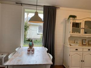 a kitchen with a wooden table and a window at Bungalow 007 in Petten