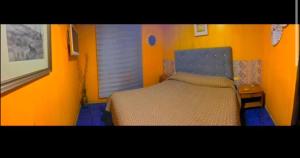 a bedroom with a bed with an orange wall at Hotel del valle in Melipilla