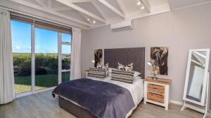 a bedroom with a large bed and a large window at La Vita Alti in Mossel Bay
