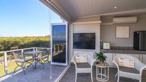 a patio with a table and chairs on a balcony at La Vita Alti in Mossel Bay