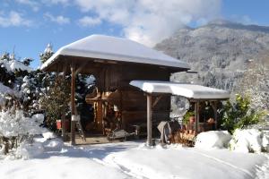 a cabin covered in snow with a mountain in the background at Séjour dans ferme de 1876 in Marignier