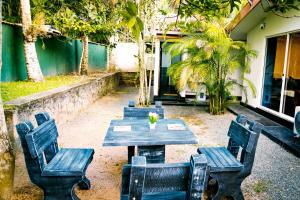a patio with a table and chairs and trees at Araliya Villa Hikkaduwa in Hikkaduwa