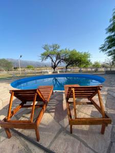 two wooden benches sitting next to a swimming pool at Complejo Chaya in La Rioja