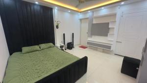 1 dormitorio con 1 cama con edredón verde y TV en Avin House, en Nabiganj