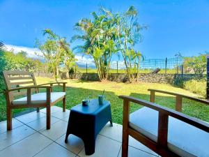 two benches and a table on a porch with a view at Le Kerbo, Calme & Jacuzzi privé à Bras-Panon in Bras-Panon