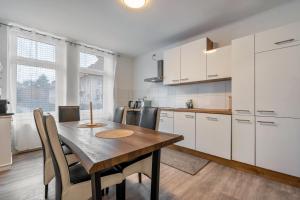 a kitchen with a wooden table and white cabinets at Ferienwohnung Am Theaterplatz in Gera