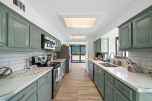 una cocina con armarios verdes y encimeras blancas en Cozy home close to Kemah Boardwalk with game room, en Clear Lake Shores