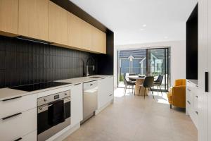 a kitchen with white cabinets and a table with chairs at Stay in the Heart of the City 3 Bed 3 Bath in Christchurch