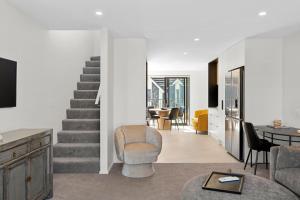 a living room with a staircase and a table and chairs at Stay in the Heart of the City 3 Bed 3 Bath in Christchurch