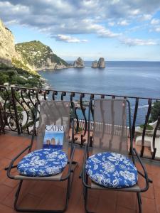 two chairs sitting on a balcony overlooking the ocean at Casa vista Faraglioni Capri in Capri