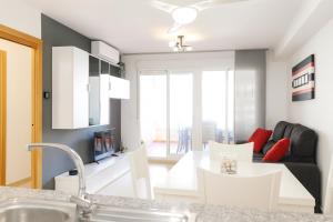 a kitchen and living room with a couch and a table at Tu refugio en Canet, piscina, parking y playa in Canet de Berenguer