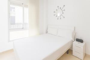 a white bedroom with a bed and a window at Tu refugio en Canet, piscina, parking y playa in Canet de Berenguer +13 photos