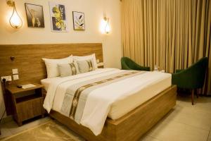 a bedroom with a large bed with two green chairs at Standard Double Room in Kigali