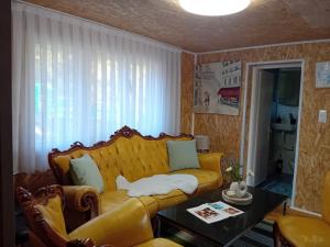 a living room with a yellow couch and a table at Gyps Vikendica with Swimming Pool and Sauna in Tuzla