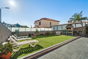 a patio with two white chairs and a lawn at Mimi Holiday House - Free Parking in Funchal