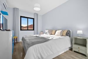 a white bedroom with a bed and a window at Mimi Holiday House - Free Parking in Funchal