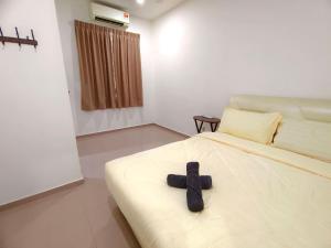 a black cross laying on a bed in a bedroom at GD Corner Lot 10pax Water Dispenser BBQ Neflix Games in Masai