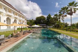 a pool with chairs and umbrellas next to a building at Ping Pura Riverside Resort & Spa Chiang Mai in Chiang Mai
