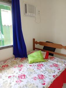 a bedroom with a bed with a floral comforter and a window at Casa da Nataliana in Cabo Frio +17 photos