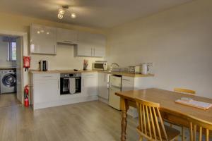 Una cocina con gabinetes blancos y una mesa de madera. en Tigh-na-mara, Helmsdale, en Helmsdale