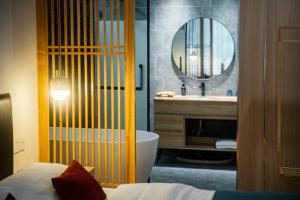 a bathroom with a tub and a sink and a mirror at Heinemann Hotel standard king room Building A with a jacuzzi and a local in Baoguosi