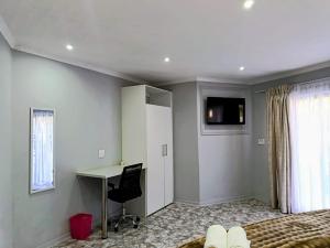 a bedroom with a bed and a desk and a computer at Lady Daisy Boutique Guesthouse in Rustenburg +12 photos