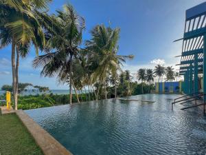 a swimming pool with palm trees and a building at Buckingham Place in Tangalle